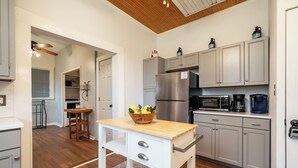 A kitchen with a wooden table, a refrigerator, cabinets, and a microwave. - The Mooney House - Hot Tub, Grill, Screen Porch, Near Downtown (Hot Springs)