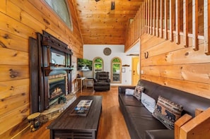 Ein gemütliches Blockhaus-Interieur mit Kamin, Ledersofa und Holzwänden.