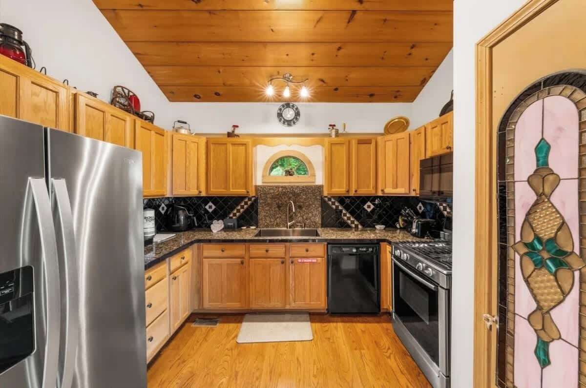 Eine Küche mit Holzausstattung, einem Edelstahlkühlschrank, einem Herd und einem Geschirrspüler.