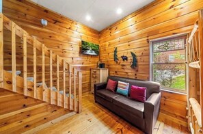 Ein Holzinnenraum mit Treppe, einer Couch und einem Fenster mit Blick.