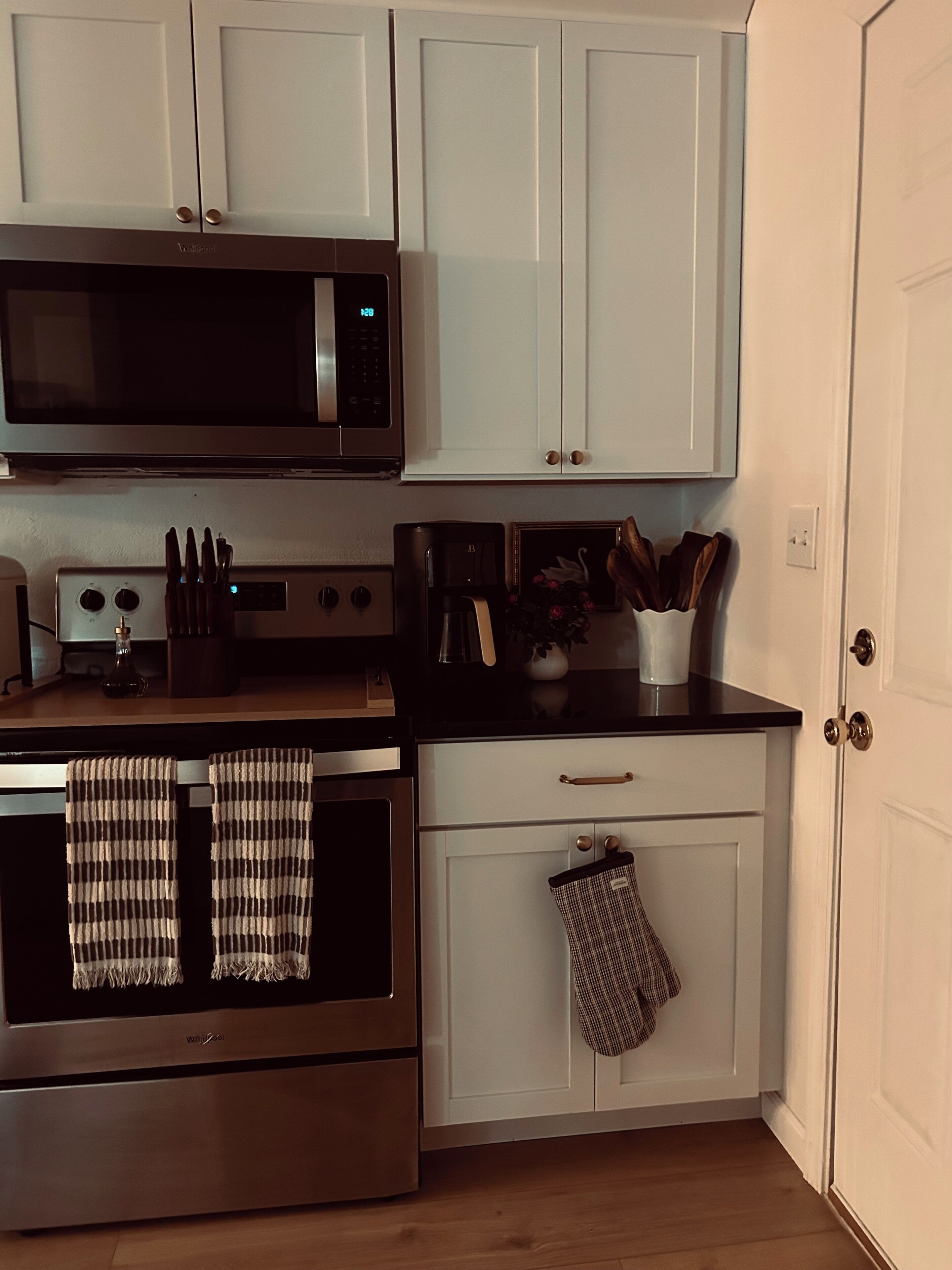 A kitchen with white cabinets, a microwave, a stove, and a coffee maker.