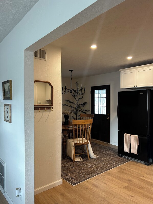 A kitchen with a dining area, wooden flooring, a chandelier, and a black refrigerator. - King suite + Hot Tub near the Greene (Dayton)