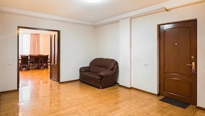 Une pièce dotée d’un plancher en bois, d’un canapé en cuir marron, d’une porte en bois et d’un coin repas bien visible, avec une table et des chaises.