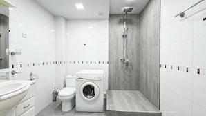 Une salle de bain moderne équipée de toilettes, d’un lave-linge et d’une douche.