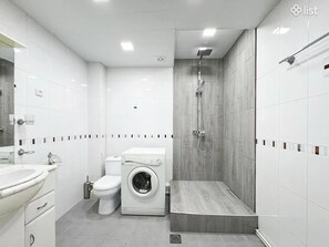 Ein modernes Badezimmer mit Toilette, Waschmaschine und Dusche.