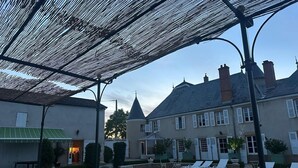 A courtyard with a pool, outdoor seating, and a building with a turret. - House with swimming pool 5 bedrooms 10 persons (Montceaux-l'Étoile)