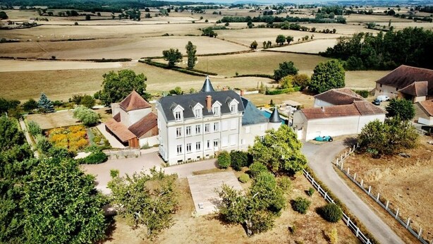 A large, historic building with multiple wings and a central tower, surrounded by expansive fields and sparse vegetation. - House with swimming pool 5 bedrooms 10 persons (Montceaux-l'Étoile)