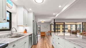 Une cuisine moderne avec des meubles blancs, un plan de travail en marbre et un plancher en bois.
