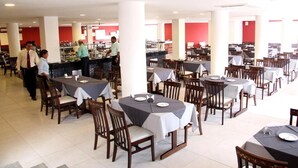 Un restaurante amplio con varias mesas y sillas, una zona de bar, y un ambiente luminoso.