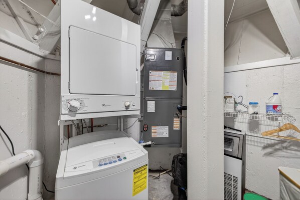 Un lavadero pequeño y funcional con lavadora blanca, calentador de agua y un refrigerador compacto.