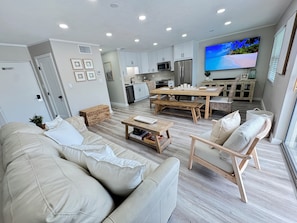 Ein modernes Wohnzimmer mit einer Couch, einem Couchtisch und einem an der Wand befestigten Fernseher.
