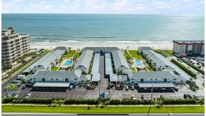 Un hotel costero con varias edificaciones, estacionamiento y vistas a la playa.