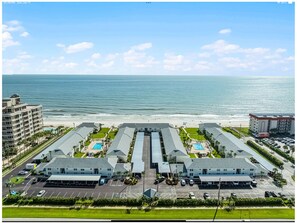 Un hôtel situé sur la côte, composé de plusieurs bâtiments, doté d’un parking et offrant une vue sur la plage.