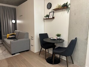 A modern living room with a grey sofa, a round table with two chairs, a clock, and a framed map on the wall. - Studio in Downtown Montreal / private balcony (Montréal)