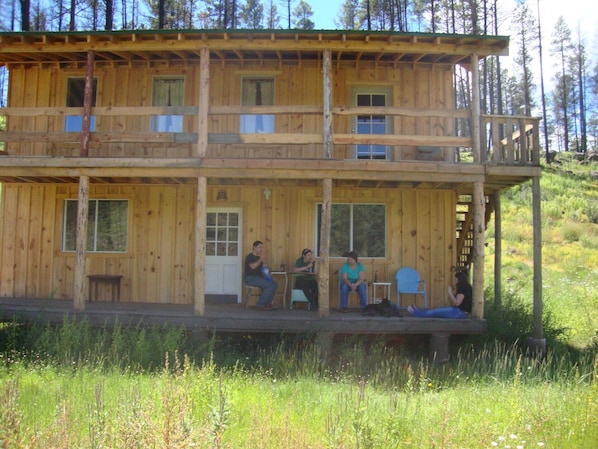 A wooden cabin with a porch and two levels.