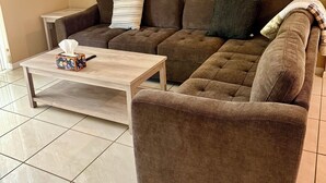 Ein Wohnzimmer mit einer braunen Couch, einem Holztisch und einem gerahmten Bild an der Wand.