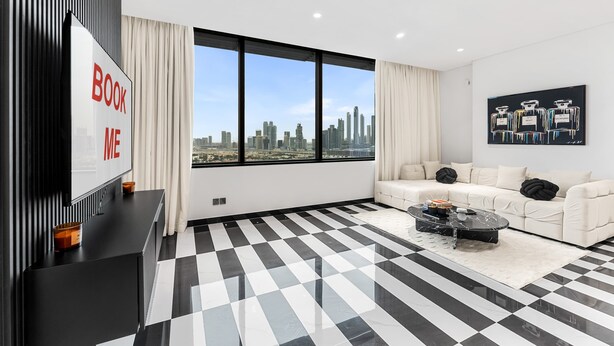 Una sala de estar moderna con piso a cuadros blanco y negro, un sofá blanco, una mesa de centro negra y un ventanal con vista a la ciudad.