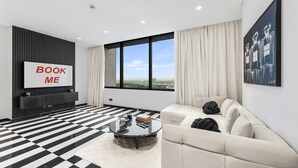 Un salón moderno con suelo a cuadros blanco y negro, un sofá, una mesa de centro y un ventanal con vistas.