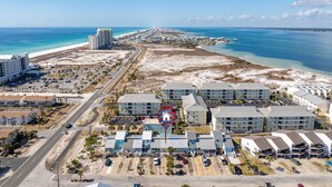 An aerial view of a coastal hotel area with beachfront properties, a main road, and a beach. - Lemon Drop Beach Cottage (Navarre)