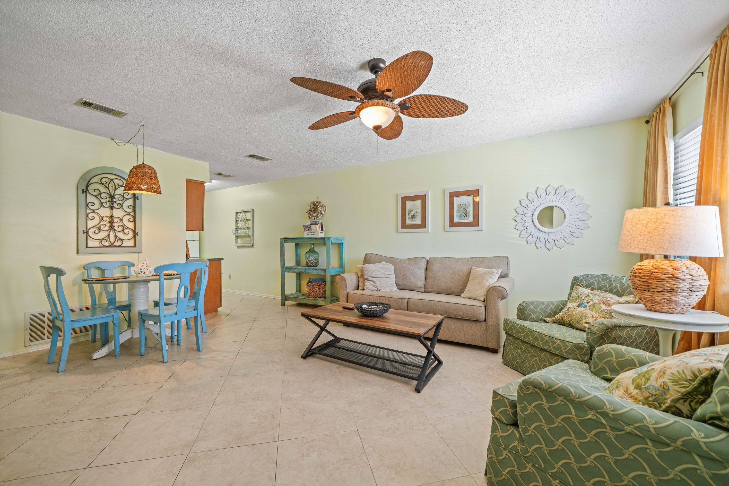A living room with a dining area, a ceiling fan, and a sofa.