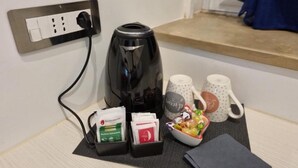 A coffee maker, two mugs, a bowl of fruit, and a black wallet on a table. - Casa Maluma - Double Room with Kitchenette in the Heart of Naples (Napoli)