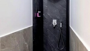 A modern bathroom with a black marble shower enclosure, a visible control panel, and a handheld showerhead. - Casa Maluma - Double Room with Kitchenette in the Heart of Naples (Napoli)