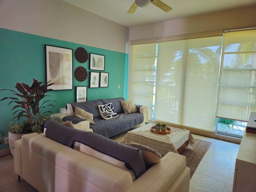 A living room with a teal accent wall, a gray sofa, a white sofa, and a coffee table with a tray.
