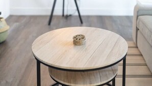 A round wooden table with a woven coaster on top, positioned in a room with a tripod in the background. - King Bed | Close to Chase Field (Phoenix)