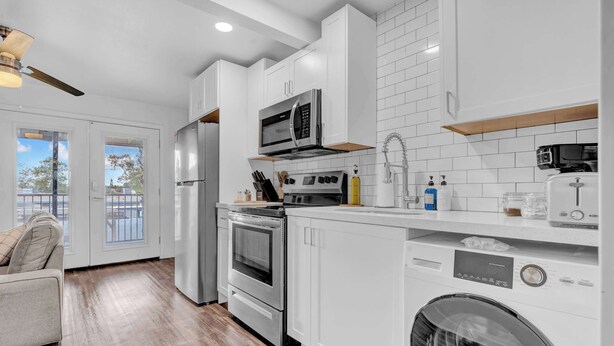 A modern kitchen with white cabinetry, stainless steel appliances, and a built-in washer and dryer. - King Bed | Close to Chase Field (Phoenix)