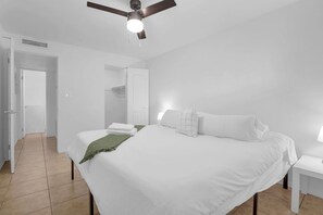 A bedroom with a large bed, a ceiling fan, and a white nightstand. - Suite in Central Phoenix with Parking (Phoenix)