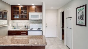 A modern kitchen with granite countertops, a white stove, and wooden cabinets. - Hotel California" La Costa Resort Life (Carlsbad)