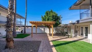 Een binnenplaats met een pergola, palmboompjes en een verzorgd gazon.