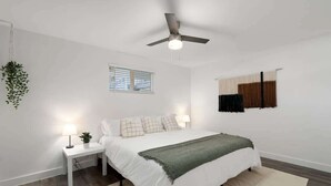 A bedroom with a bed, bedside tables, a ceiling fan, a window, and a hanging plant. - Midtown 2 King| Near Roosevelt Row (Phoenix)