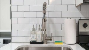 A modern kitchen with a stainless steel sink, a dish soap dispenser, a hand soap dispenser, a paper towel holder, and a built-in oven. - Midtown 2 King| Near Roosevelt Row (Phoenix)
