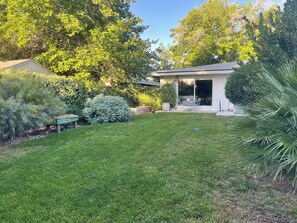 Un jardin bien entretenu, avec une pelouse, du mobilier de jardin et une variété de plantes et d’arbres.