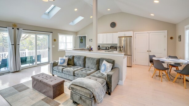 A spacious living area with a gray sectional sofa, a dining table with chairs, a kitchen with white cabinets, and a ceiling fan. - 6 Mi to Tanglewood! High-End Lee Apartment (Lee)