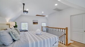 A bedroom with a bed, a nightstand, a lamp, a window, and a door. - Remodeled 4BR w/ Yard, Fire Pit, Near Camelback (Tannersville)