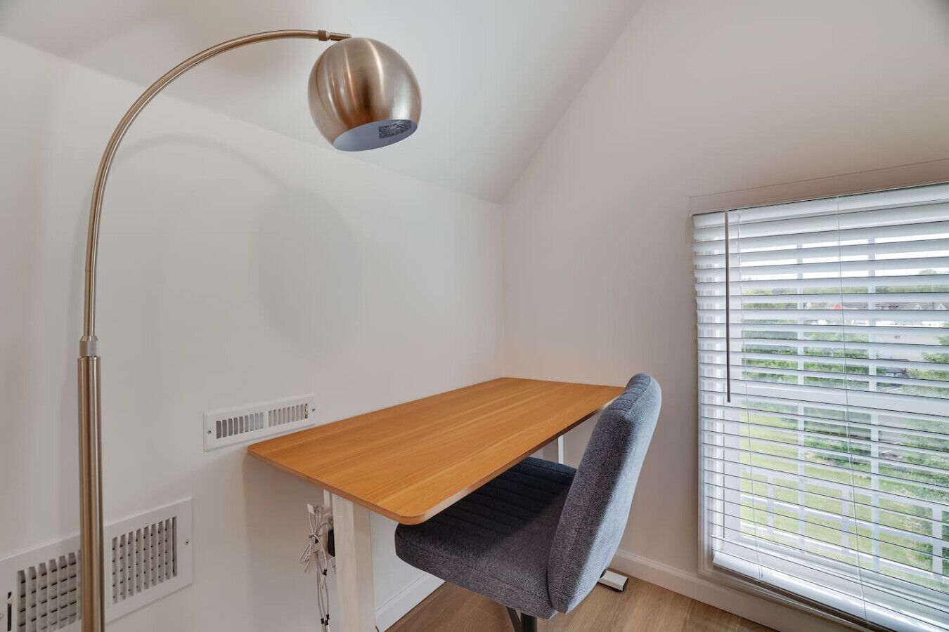 Een hoekkamer met een bureau, stoel en vloerlamp.