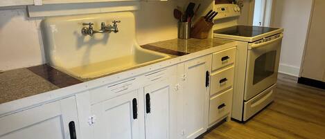 A kitchen with white cabinets, a sink, a stove, and a countertop.