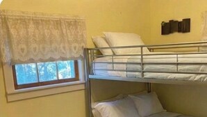 Una camera con letto a castello, finestra e decorazioni a parete, con una tenda in pizzo.