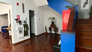 A spacious room with a herringbone wood floor, a blue and brown staircase, and a black couch. - Haku Hostel Lima (Lima)