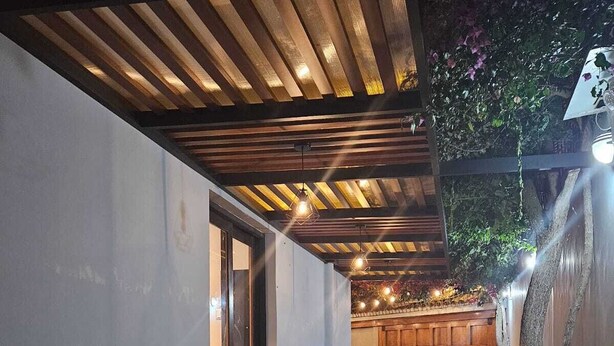 An outdoor patio with wooden tables and chairs, a checkered floor, and a wooden ceiling. - Haku Hostel Lima (Lima)