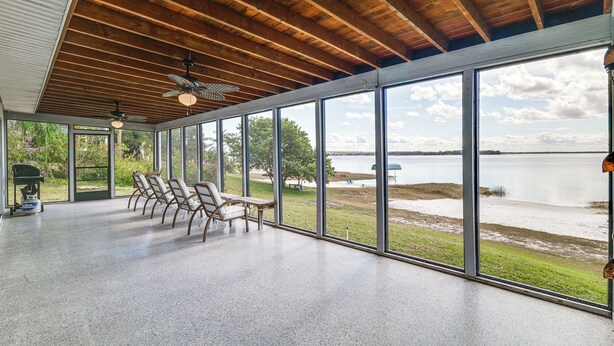A spacious room with large windows, wooden ceiling beams, and a view of a lake. - Water Access + Beach Area: Crooked Lake Escape (Babson Park)
