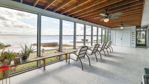 A spacious room with large windows, a wooden ceiling, and a bench with chairs. - Water Access + Beach Area: Crooked Lake Escape (Babson Park)