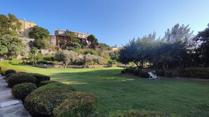 A well-maintained grassy area with a stone pathway, neatly trimmed bushes, and a white lounge chair. - Cappuccini apartment a few minutes walk from the center (Cagliari)