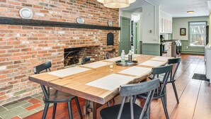 A dining area with a brick wall, wooden table, and black chairs. - Dine & Unwind! Overlook Home at Rabbit Hill Inn (Lower Waterford)