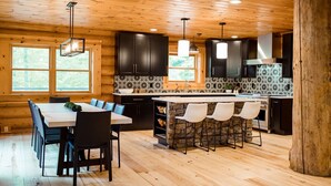 Une cuisine moderne avec des meubles en bois, un grand îlot central doté de tabourets, et un coin repas avec une table et des chaises.