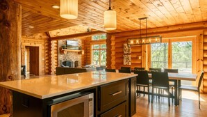 L’intérieur d’une cabane en rondins comprend une cuisine, un coin repas et une cheminée.