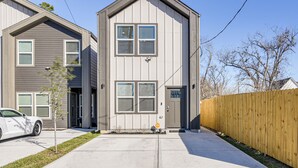 A two-story residential building with a front door, a garage, and a driveway. - Sleek, Convenient New-Build 8 Mi to Dtwn Houston! (Houston)