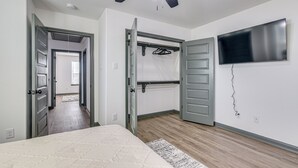 A bedroom with a bed, a ceiling fan, a TV, and a walk-in closet. - Sleek, Convenient New-Build 8 Mi to Dtwn Houston! (Houston)